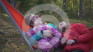 Happy family with child spend time hammock during weekend in camping.