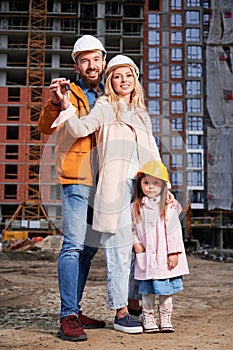 Happy family with child standing outdoors at construction site.