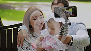 Happy family with a child take a selfie on a bench in the park.