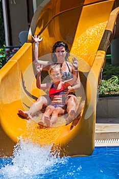 Happy family with child on water slide at aquapark