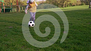 Happy Family Of Children Having Fun In Spring Park. Little Kid Run. Child Girl Dribbles Black White Classic Soccer Ball