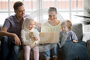 Happy family with children having fun using laptop on sofa