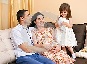 Happy family with children indoor portrait, pregnant woman and man, beautiful people portrait sit on sofa