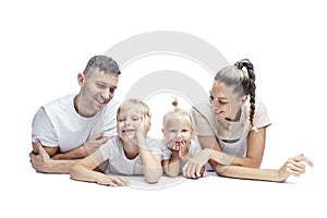 Happy family with children lying on their stomach. Mom, dad, daughter and son in white T-shirts hug and laugh. Love and tenderness