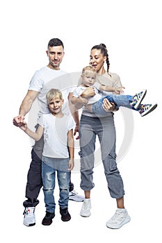 Happy family with children. Mom, dad, daughter and son in white T-shirts and jeans hug and laugh.