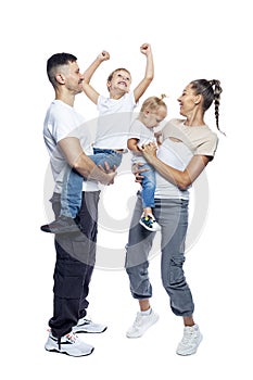 Happy family with children. Mom, dad, daughter and son in white T-shirts and jeans hug and laugh. Love and tenderness. Full height