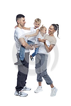 Happy family with children. Mom, dad, daughter and son in white T-shirts and jeans hug and laugh. Love and tenderness. Full height