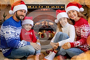 Happy family with children near fireplace at Christmas