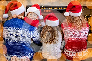 Happy family with children near fireplace at Christmas