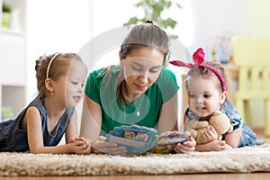 Happy family with children read a story laying on the floor in the kids room