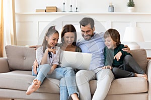 Happy family with children relaxing on couch with laptop