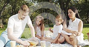 Happy family with children resting on the grass during a picnic in the green garden