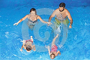 Happy family with children swimming with fun in blue pool