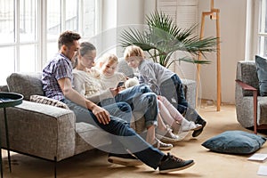 Happy family with children using mobile apps together on sofa