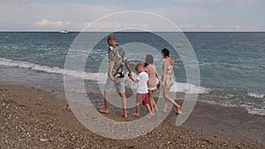 A happy family with children walking along the seashore at sunset.