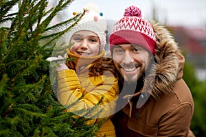 Happy family choosing christmas tree at market