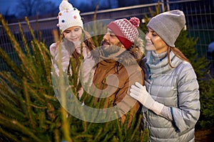 Happy family choosing christmas tree at market