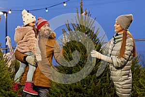 Happy family choosing christmas tree at market