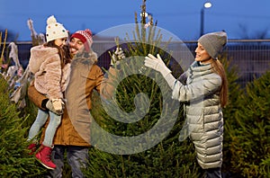 Happy family choosing christmas tree at market