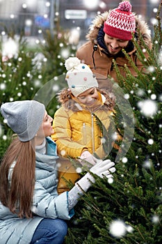 Happy family choosing christmas tree at market