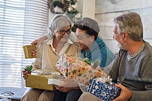 Happy family in christmas eve day with grandfathers and grandson teenager having fun with gift exchange activity at home on the