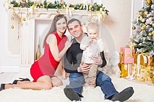 Happy family at Christmas eve sitting together near fireplace