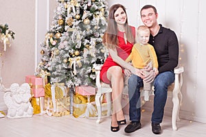 Happy family at Christmas eve sitting together near fireplace