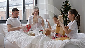 happy family with christmas gifts in bed at home