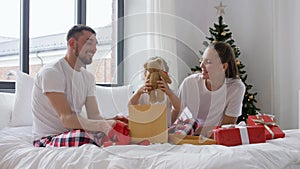 happy family with christmas gifts in bed at home