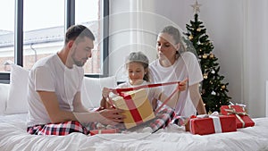 Happy family with Christmas gifts in bed at home