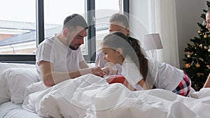 Happy family with Christmas gifts in bed at home