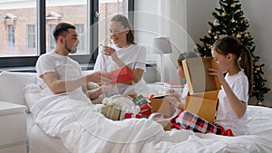 Happy family with Christmas gifts in bed at home