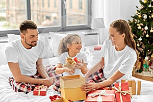 happy family with christmas gifts in bed at home