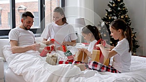 happy family with christmas gifts in bed at home
