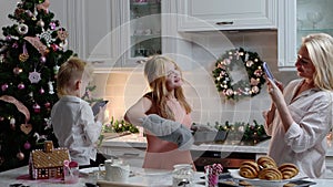 Happy family Christmas - a girl takes out the baking sheet and her mom taking pictures of her