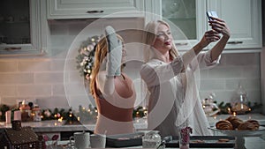 Happy family christmas - mom shooting a video with her daughter in the kitchen