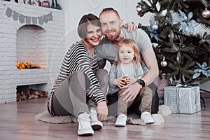 Happy family at christmas in morning opening gifts together near the fir tree