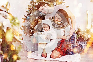 Happy family at christmas in morning opening gifts together near the fir tree. The concept of family happiness and well