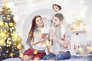 Happy family at christmas in morning opening gifts together near the fir tree. The concept of family happiness and well