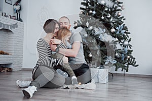 Happy family at christmas in morning opening gifts together near the fir tree. The concept of family happiness and well