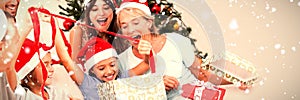 Composite image of happy family at christmas opening gifts together