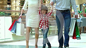 Happy Family Christmas shopping in mall. The boy holds a hand the mother and the father. Parents and child with packages