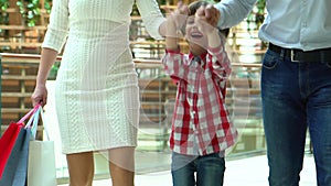 Happy Family Christmas shopping in mall. The boy holds a hand the mother and the father. Parents and child with packages