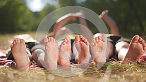 happy family. close-up of a kids leg feet lie on the grass in the summer park. children feet close-up team together