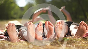 happy family. close-up of a kids leg feet lie on the grass in the summer park. children feet close-up team together