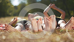 happy family. close-up of a kids leg feet lie on the grass in the summer park. children feet close-up team together