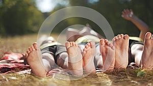 happy family. close-up of a kids leg feet lie on the grass in the summer park. children feet close-up team together