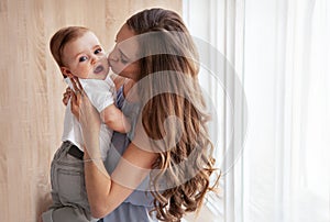 Happy family. Close up portrait of young attractive mother holding baby in her arms and gently kissing son