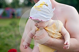 Happy family: a close up portrait of young dad holding his cute newborn baby in summer