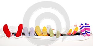 Happy family in colorful socks on white bed.